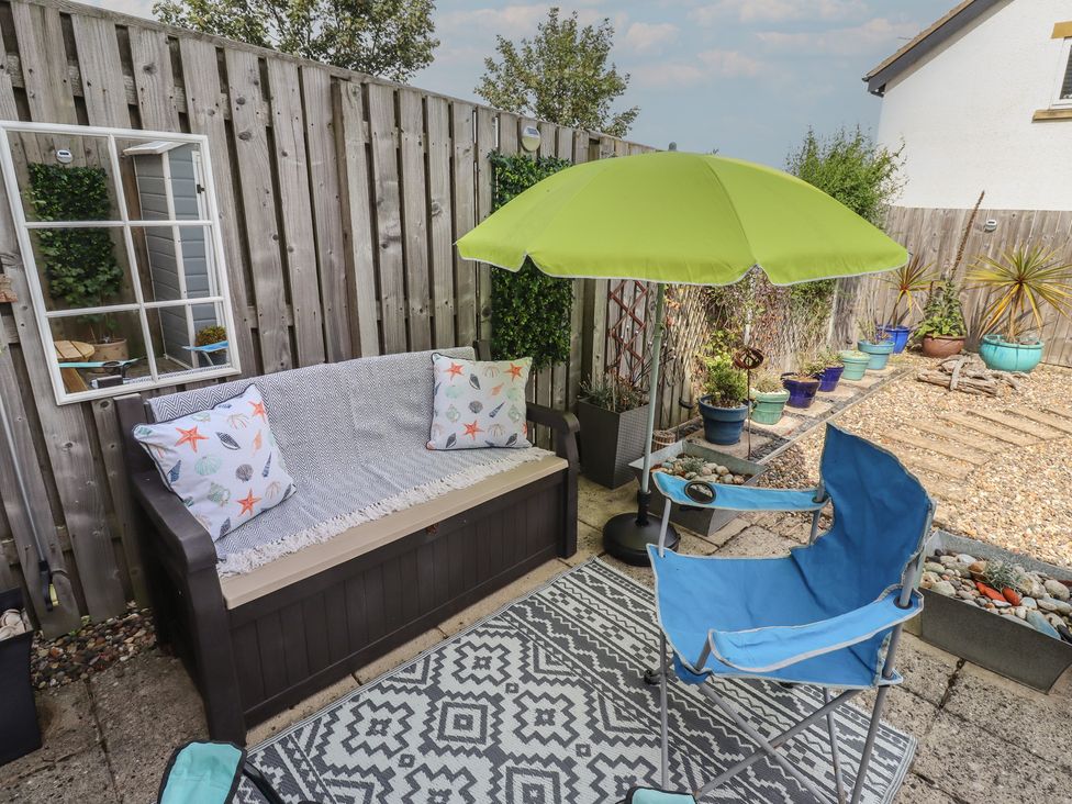A garden area with a bench and an umbrella at Tidal Watch in Seahouses