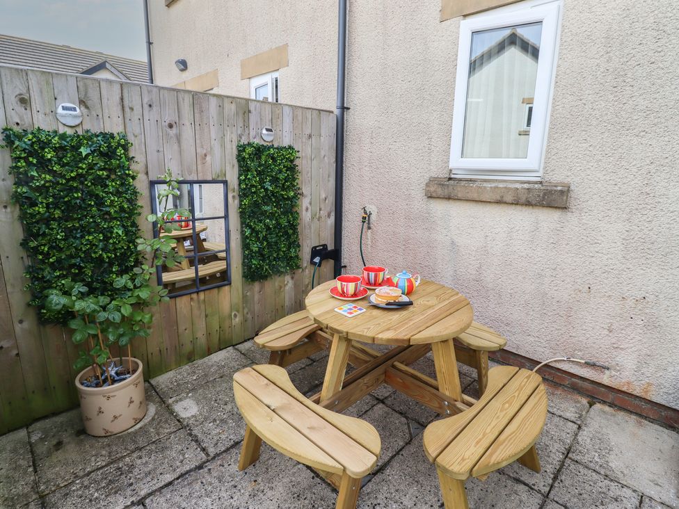 A patio with a wooden table and chairs at Tidal Watch in Seahouses