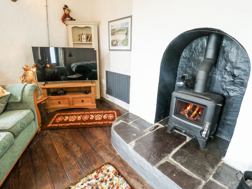 A living room with a television and fireplace at The Old Cornmill in Cemaes Bay