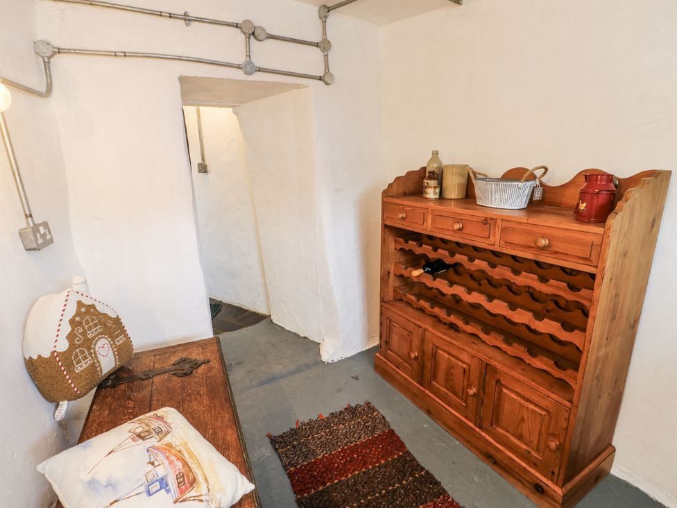 A hallway with a wine rack and wooden bench at The Old Cornmill in Cemaes Bay