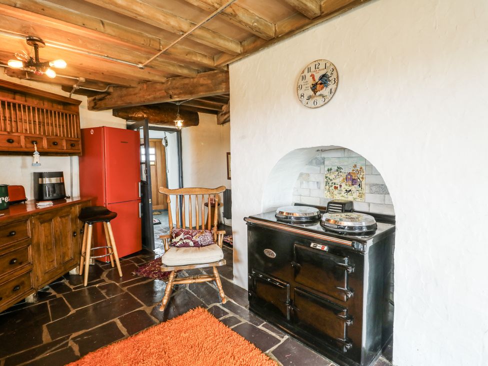 A kitchen with a red refrigerator and a wooden chair at The Old Cornmill in Cemaes Bay