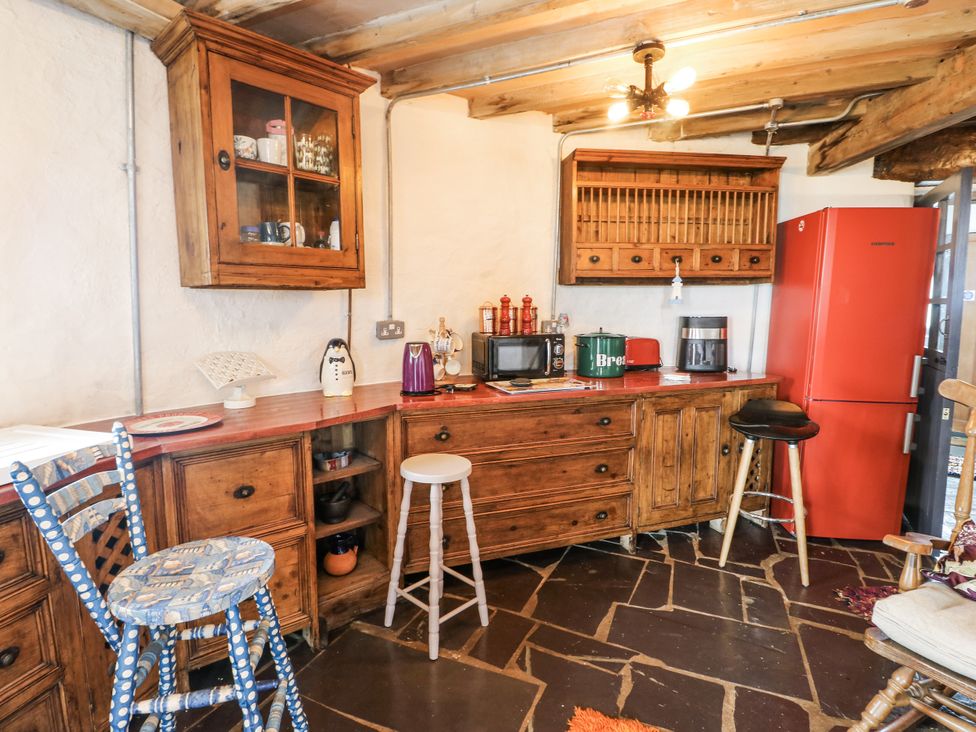 A kitchen with wooden cabinets and appliances at The Old Cornmill in Cemaes Bay