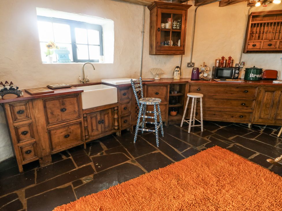 A kitchen with wooden cabinets and a sink at The Old Cornmill in Cemaes Bay