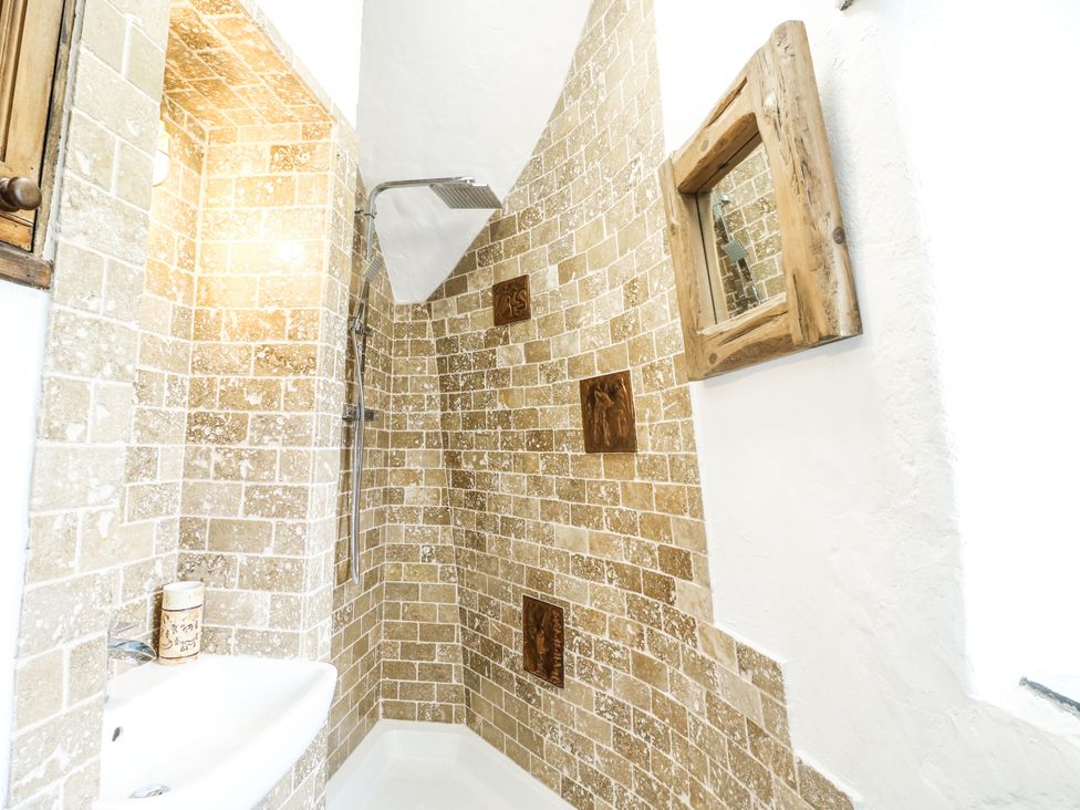 A shower with a wall and mirror at The Old Cornmill in Cemaes Bay