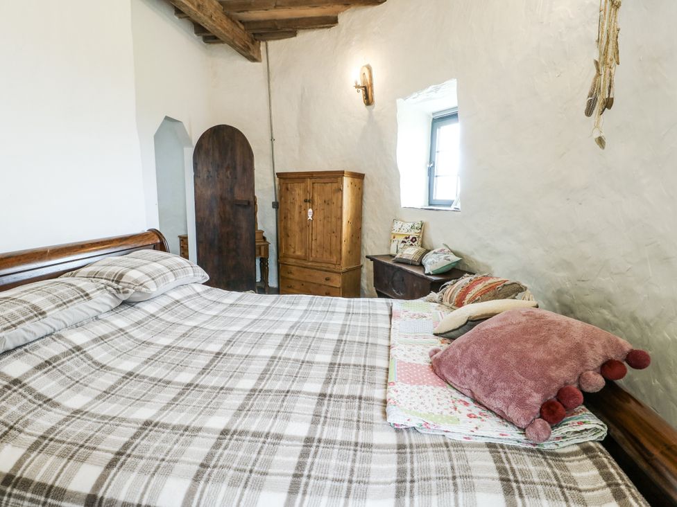 A bedroom with a bed and wooden furniture at The Old Cornmill in Cemaes Bay
