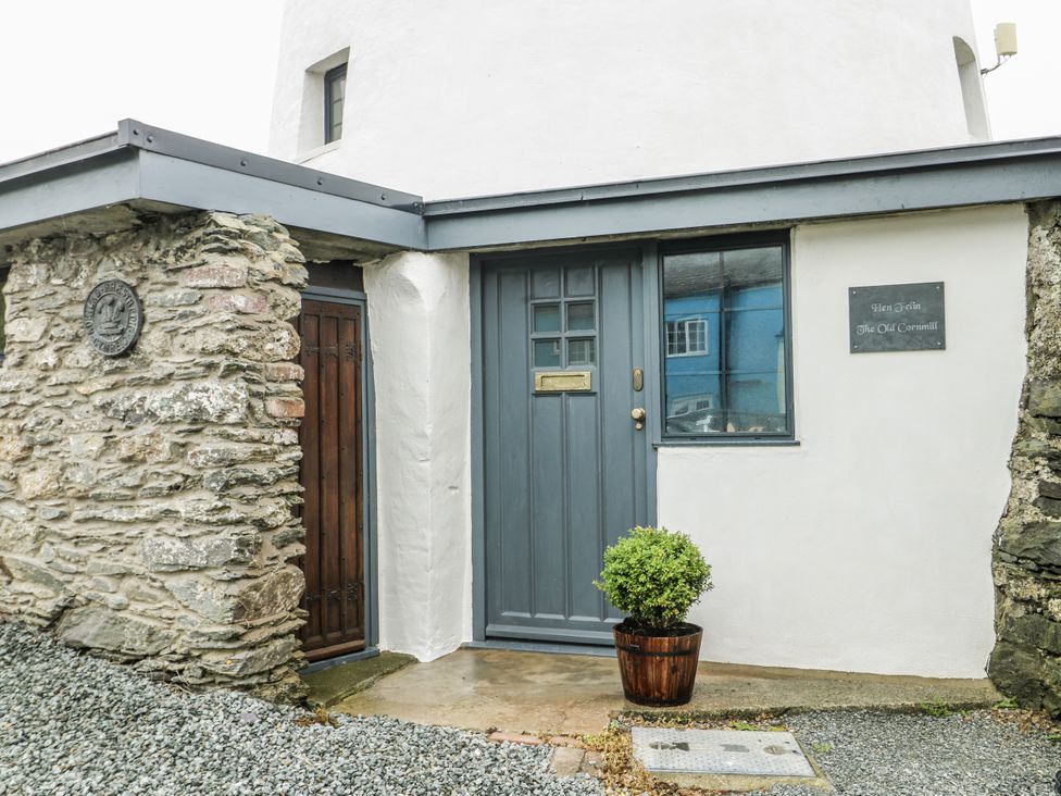 An entrance with a grey door and stone wall at The Old Cornmill in Cemaes Bay