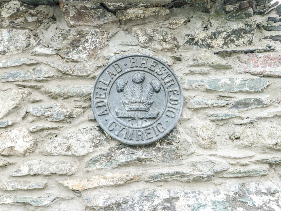 A metal plaque mounted on a stone wall at The Old Cornmill in Cemaes Bay