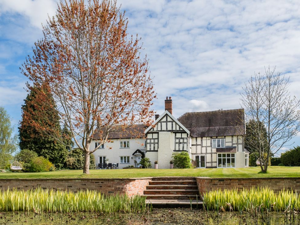 A house surrounded by a garden with trees and a water feature at Hall O'Coole in Broomhall nearn Wrenbury