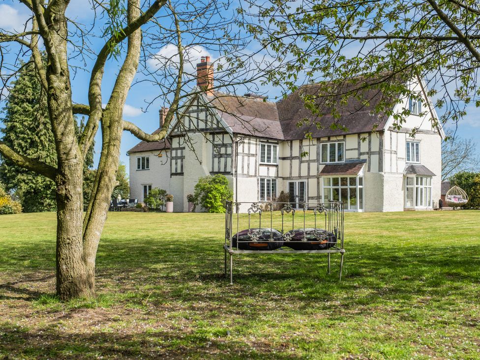A house with a lawn and a swing in the garden at Hall O'Coole in Broomhall nearn Wrenbury