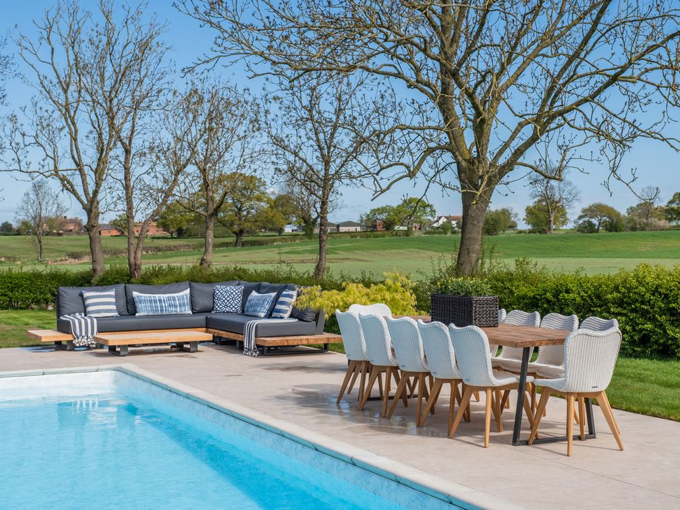 An outdoor area with a swimming pool, sofa and dining set at Hall O'Coole in Broomhall nearn Wrenbury