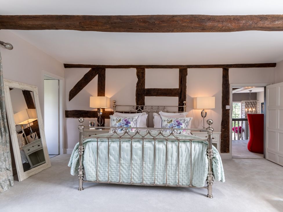 A bedroom with wooden beams and a metal bed frame at Hall O'Coole in Broomhall near Wrenbury
