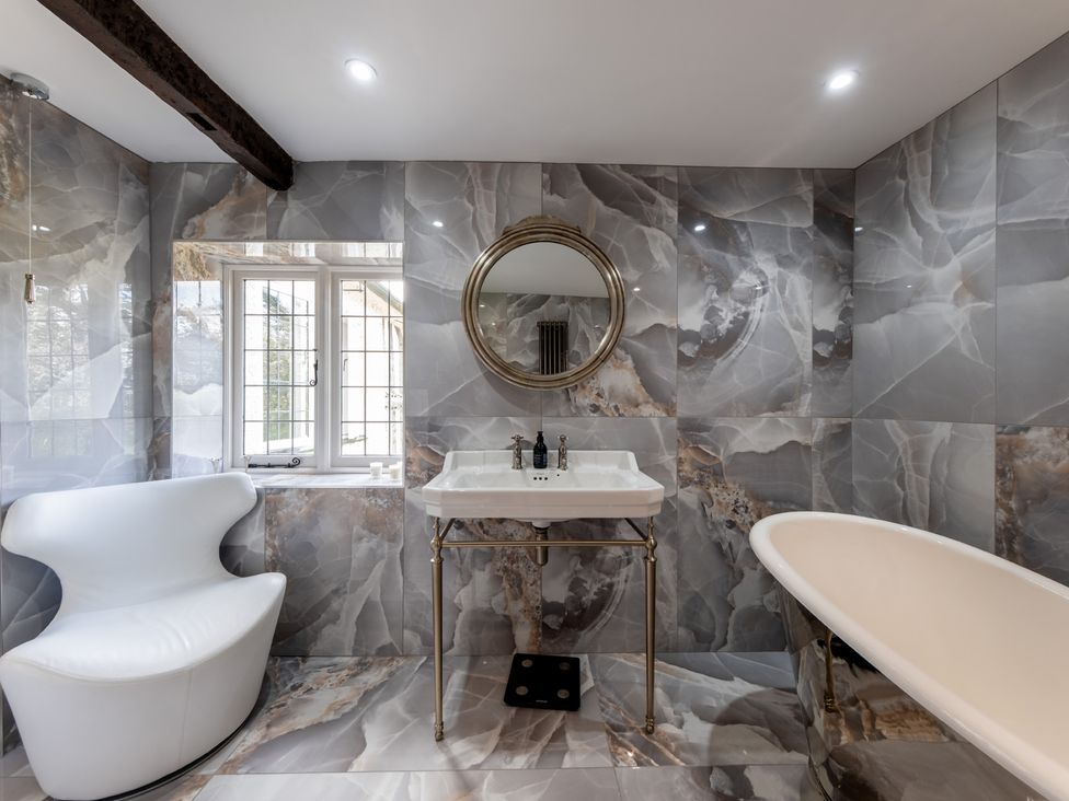 A bathroom with a bathtub, washbasin, and mirror at Hall O'Coole in Broomhall near Wrenbury