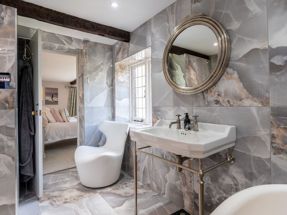 A bathroom with a sink, mirror, and chair at Hall O'Coole in Broomhall nearn Wrenbury