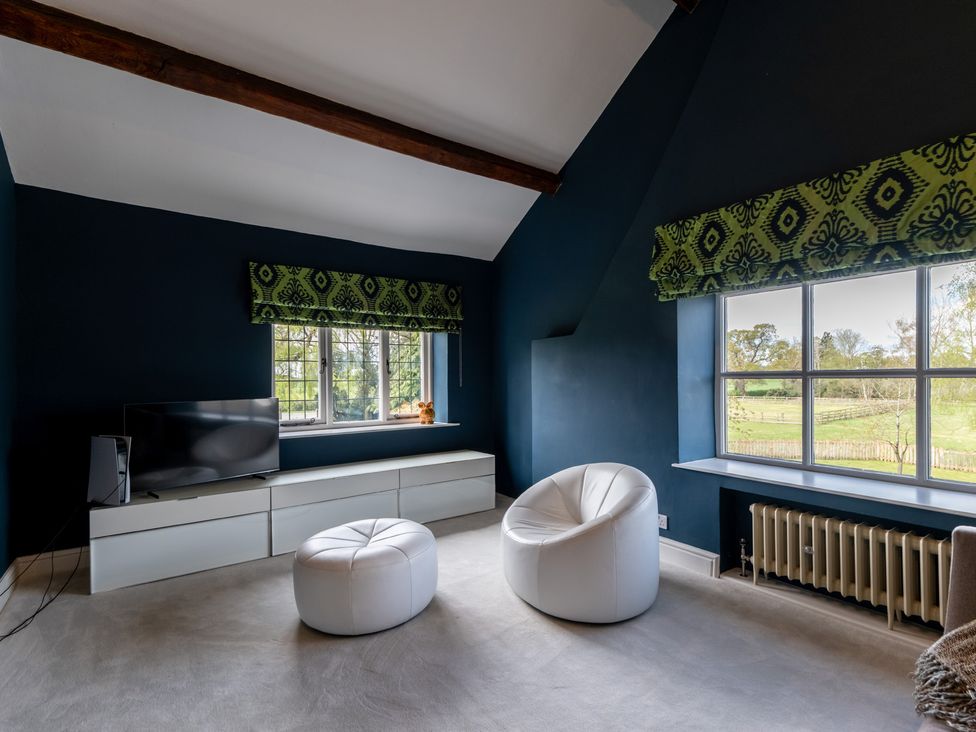 A living room with a television and white chairs at Hall O'Coole in Broomhall nearn Wrenbury