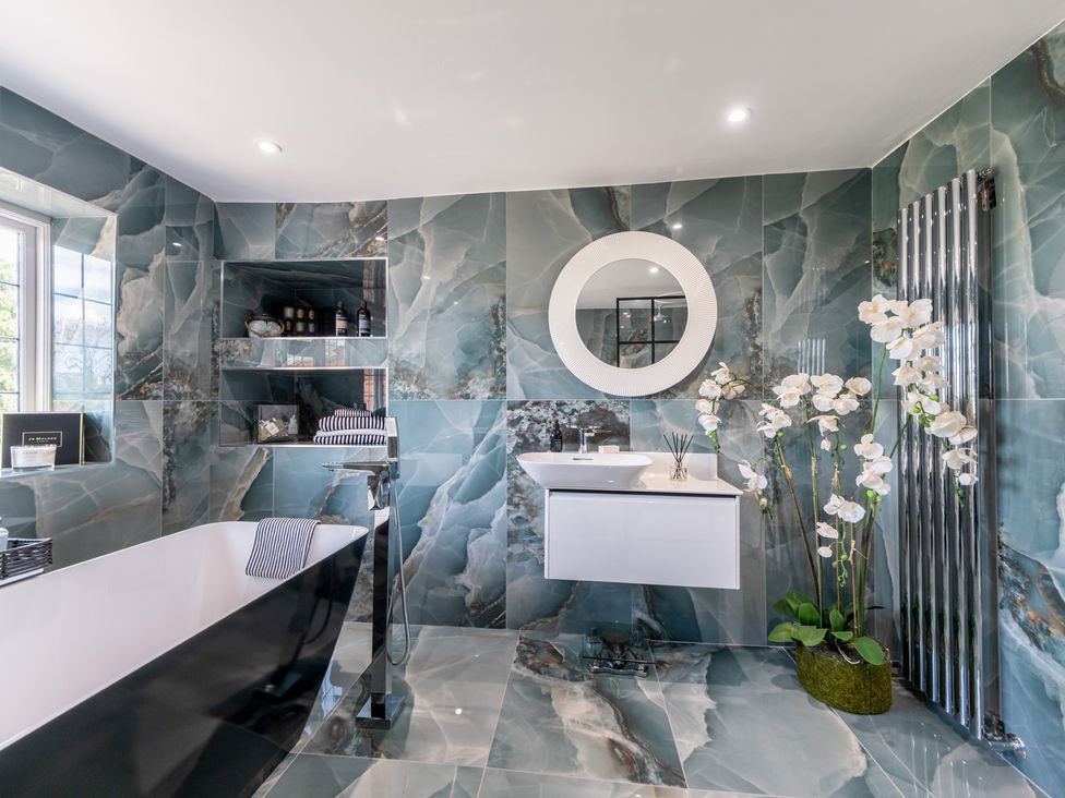 A bathroom with a bathtub, sink, and shelf at Hall O'Coole in Broomhall near Wrenbury