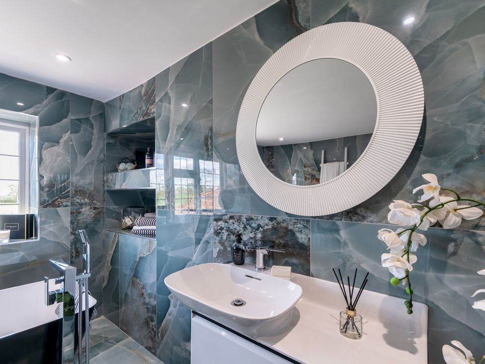 A bathroom featuring a washbasin, mirror, and bathtub at Hall O'Coole in Broomhall near Wrenbury