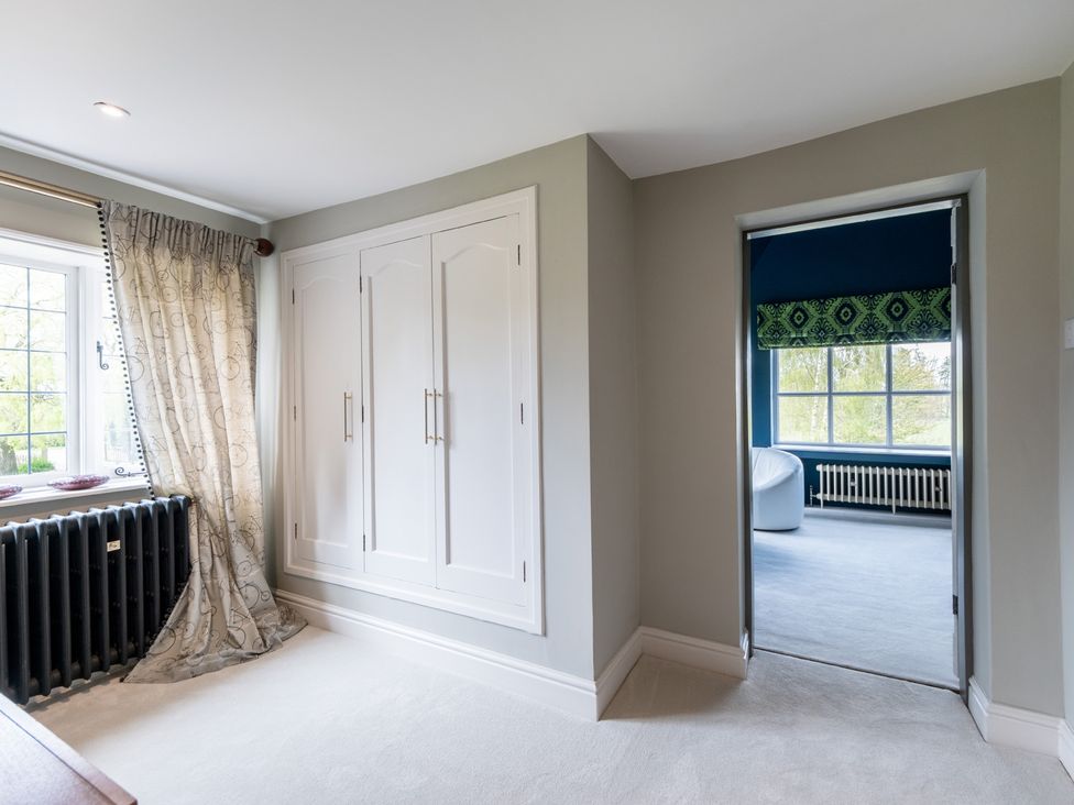 A bedroom with a wardrobe and a window at Hall O'Coole in Broomhall near Wrenbury