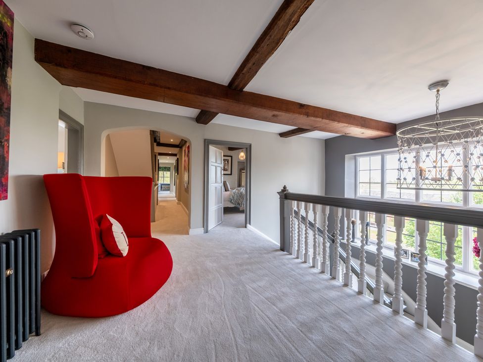 A hallway with a red chair and staircase at Hall O'Coole Broomhall nearn Wrenbury