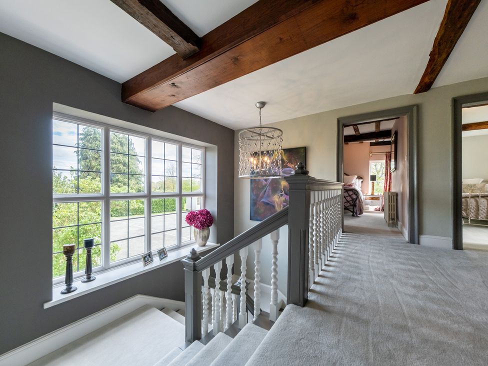 A hallway with a staircase and windows at Hall O'Coole in Broomhall near Wrenbury