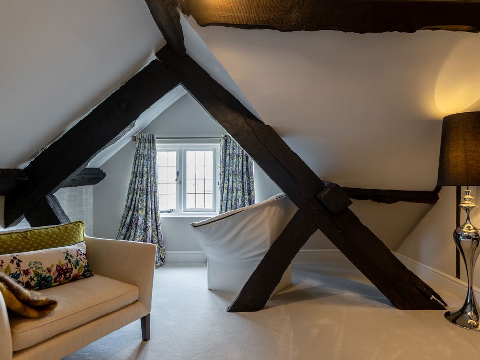 An attic with beams and an armchair at Hall O'Coole in Broomhall nearn Wrenbury
