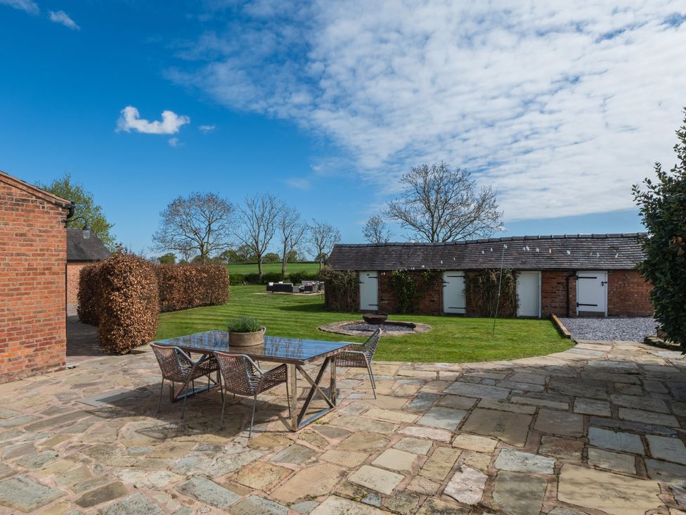 An outdoor area with a stone patio and seating arrangements at Hall O'Coole in Broomhall near Wrenbury