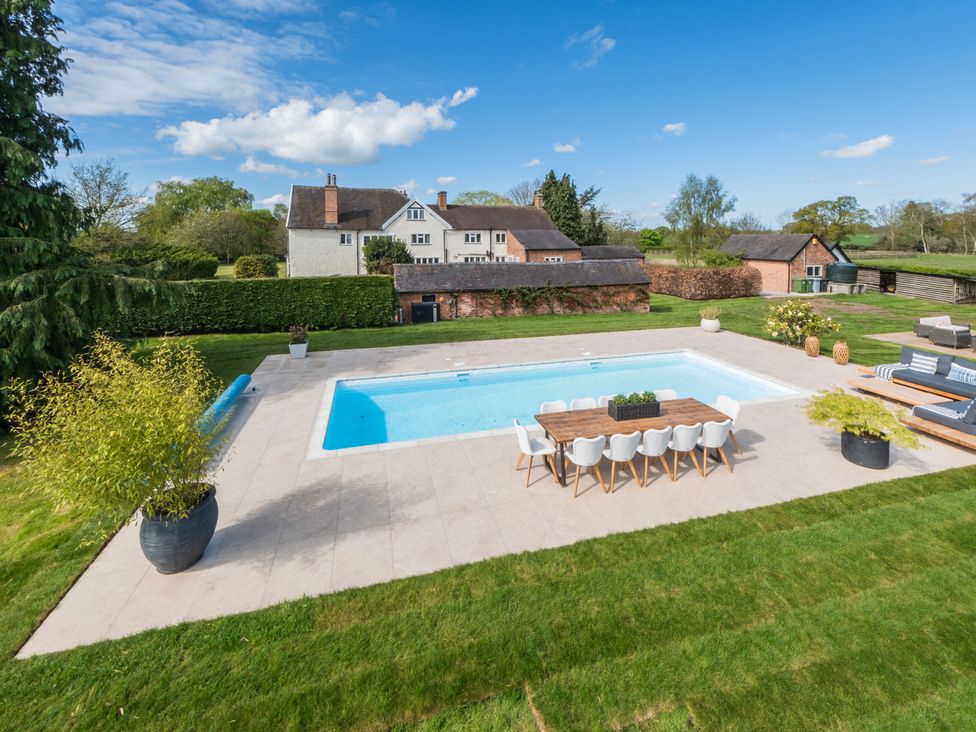 An outdoor area with a swimming pool and dining table at Hall O'Coole in Broomhall nearn Wrenbury