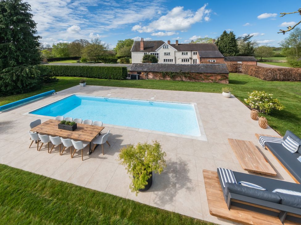 A garden with a swimming pool and dining setup at Hall O'Coole in Broomhall nearn Wrenbury