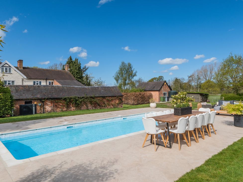 An outdoor area featuring a swimming pool and a dining table with chairs at Hall O'Coole in Broomhall nearn Wrenbury