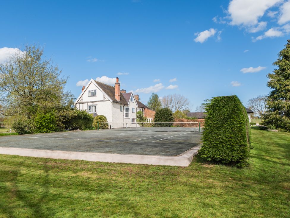 An outdoor area with a tennis court and a house at Hall O'Coole in Broomhall nearn Wrenbury