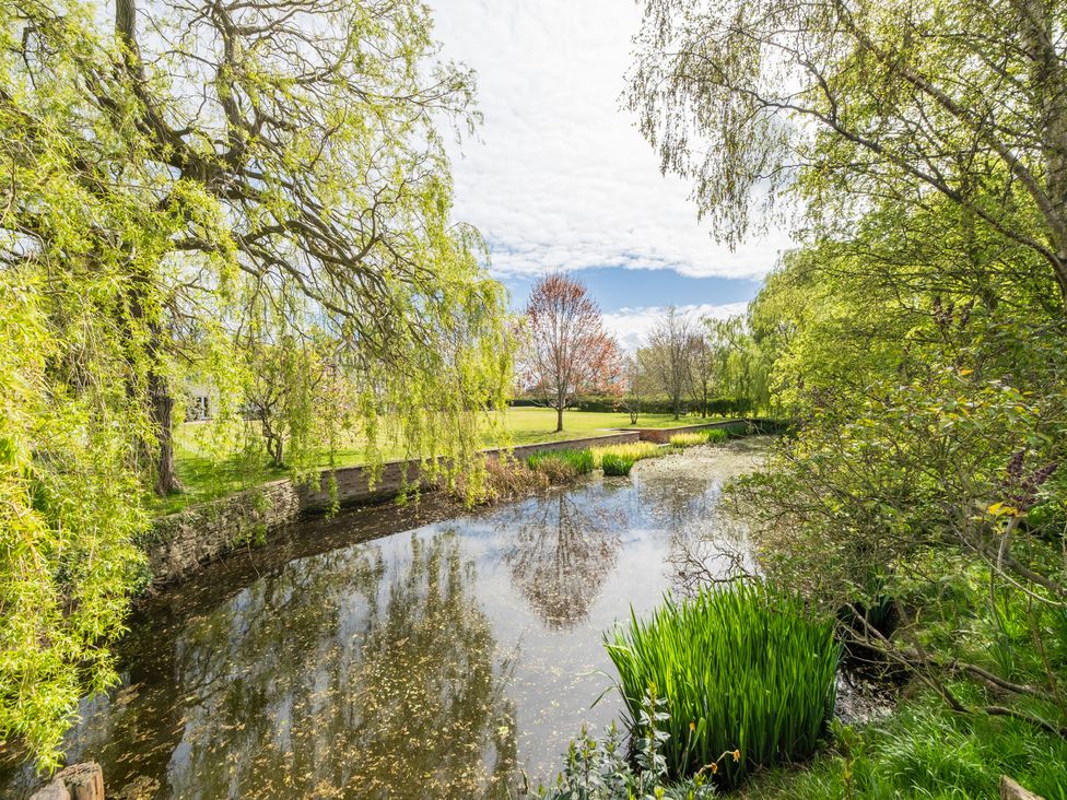 A pond with surrounding trees and grass at Hall O'Coole in Broomhall nearn Wrenbury
