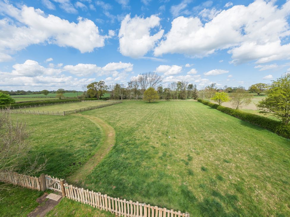 An outdoor view of a green field with trees and a fence at Hall O'Coole Broomhall near Wrenbury