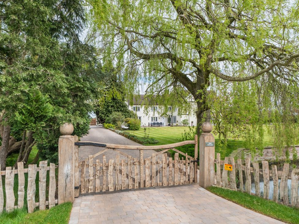 A gate leading to a pathway with trees and a house in the background at Hall O'Coole in Broomhall nearn Wrenbury