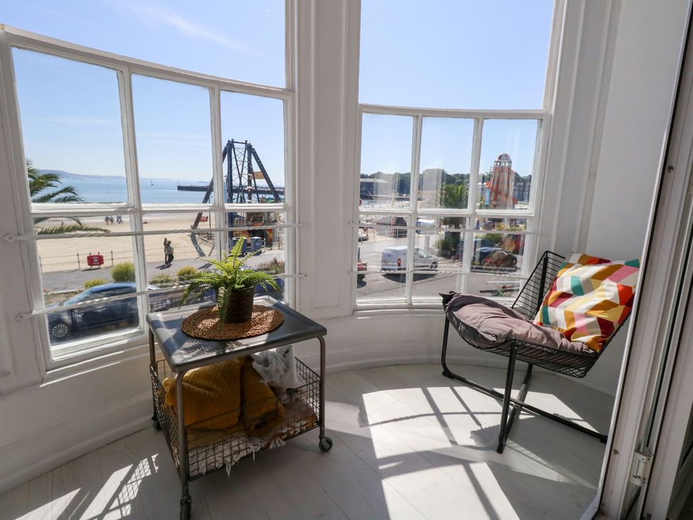 A sunroom with a chair and table overlooking the beach at The Beach Condo in Weymouth