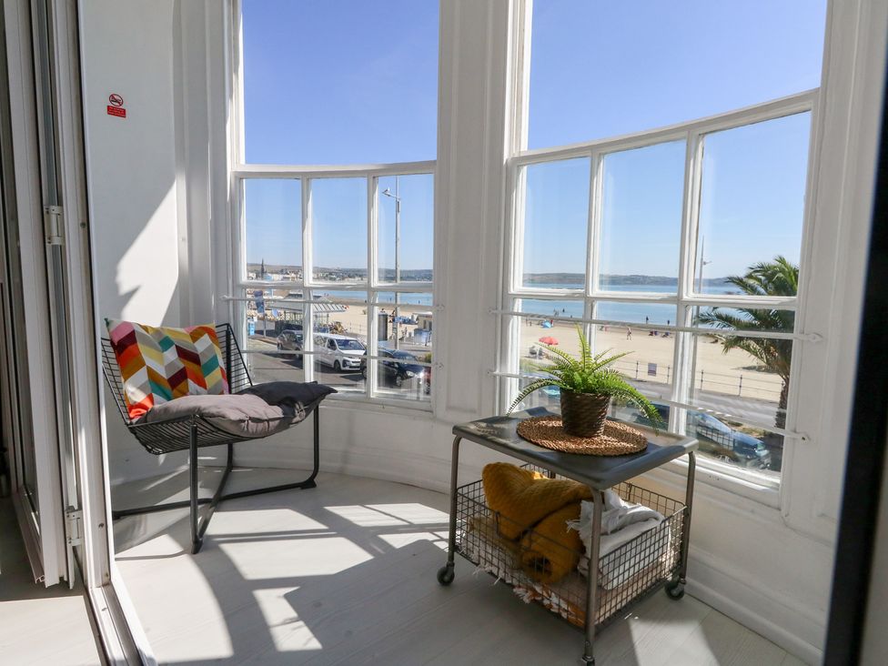 A balcony with a chair and table overlooking the beach at The Beach Condo in Weymouth