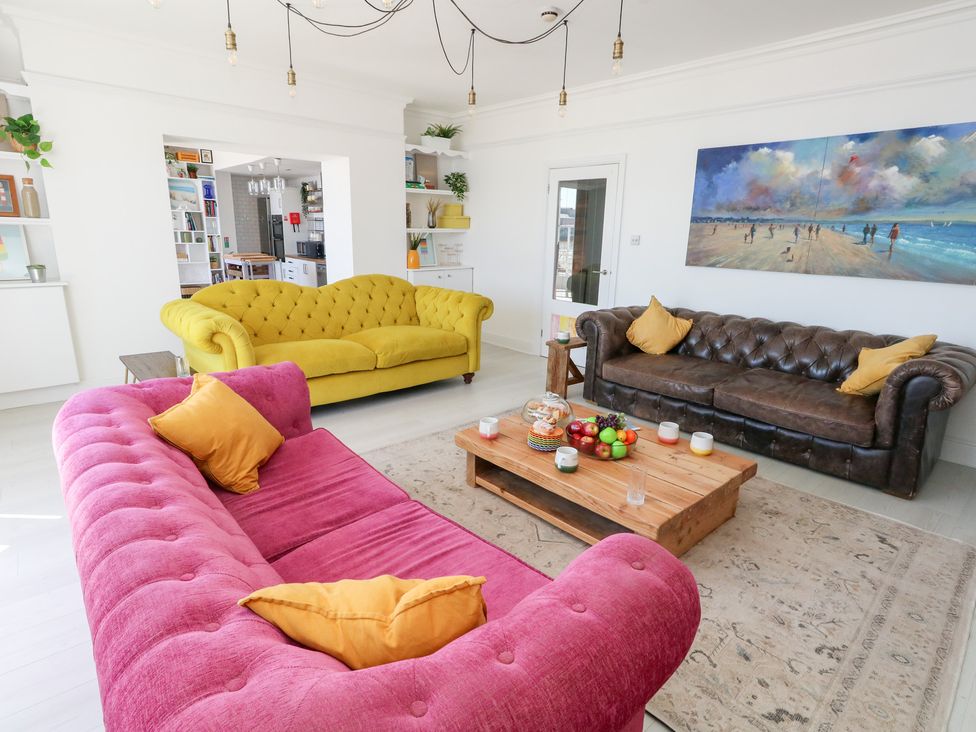 A living room with colorful sofas and a coffee table at The Beach Condo in Weymouth