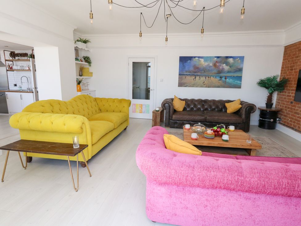 A living room with colorful sofas and a coffee table at The Beach Condo in Weymouth