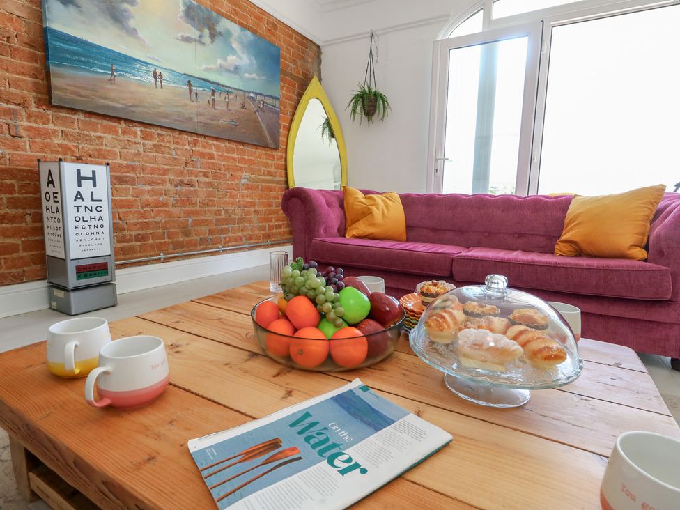 A living room with a sofa, table, and fruit bowl at The Beach Condo in Weymouth