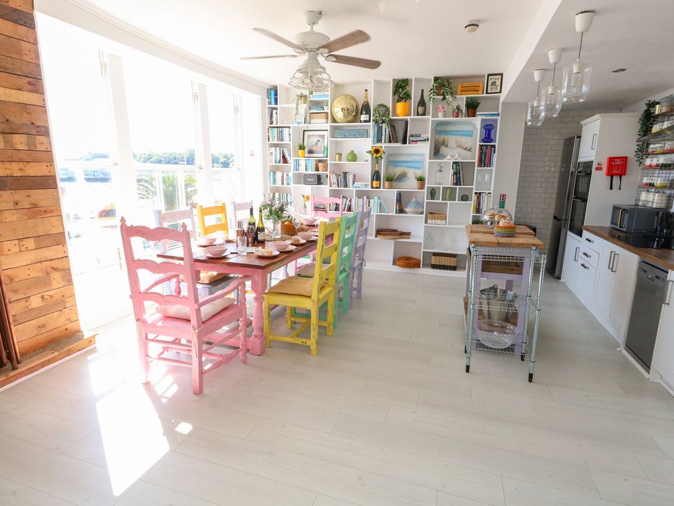 A dining room with a table and colorful chairs at The Beach Condo in Weymouth