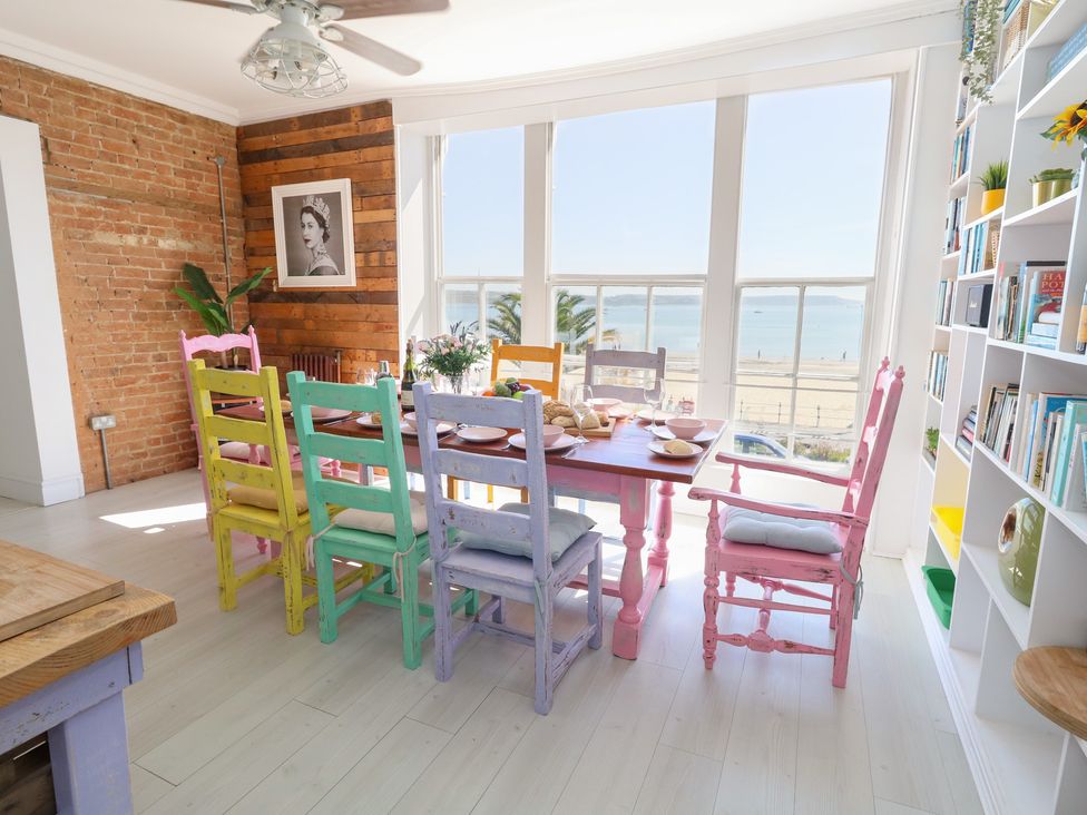A dining room with a table and colorful chairs at The Beach Condo in Weymouth