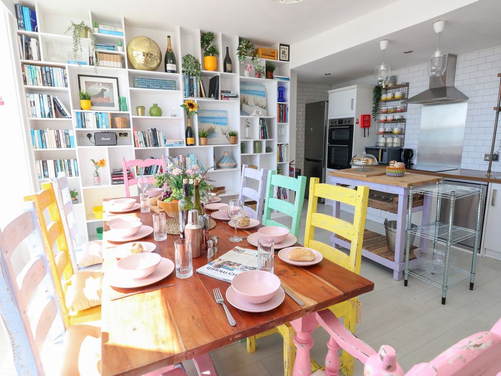A dining room with a wooden table set for a meal at The Beach Condo in Weymouth