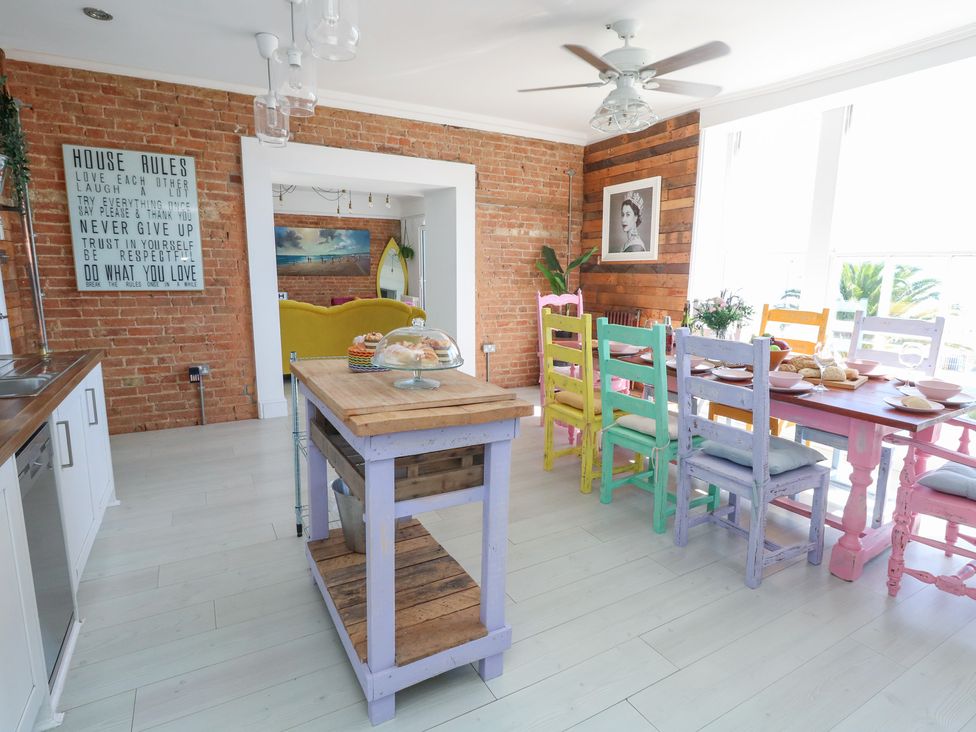 A dining room with an island and colorful chairs at The Beach Condo in Weymouth