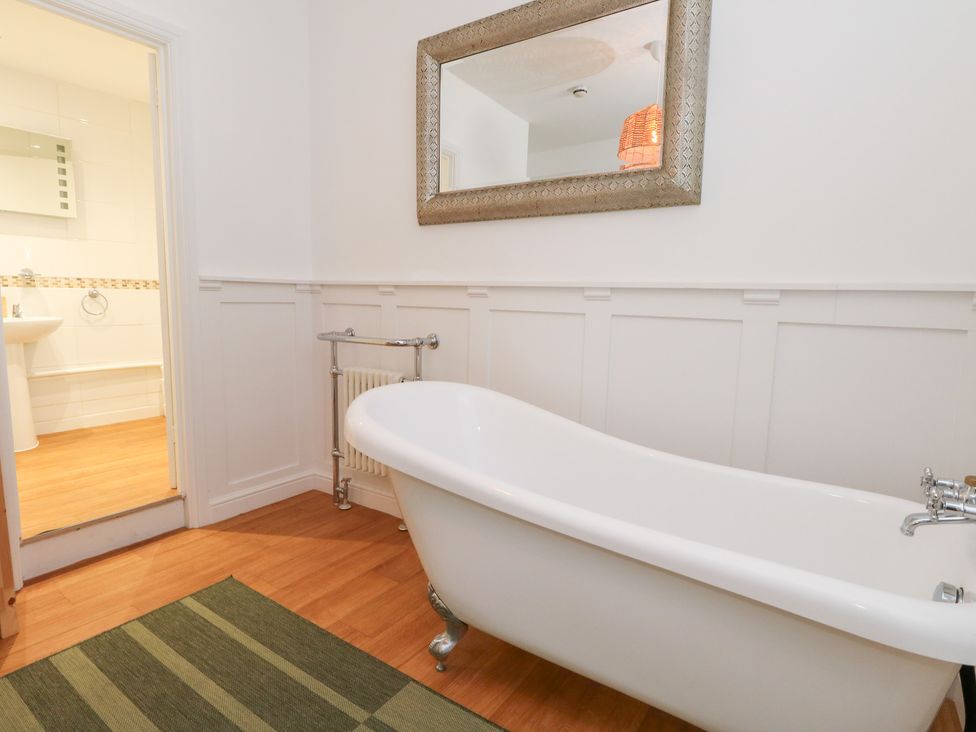 A bathroom with a bathtub and mirror at The Beach Condo in Weymouth