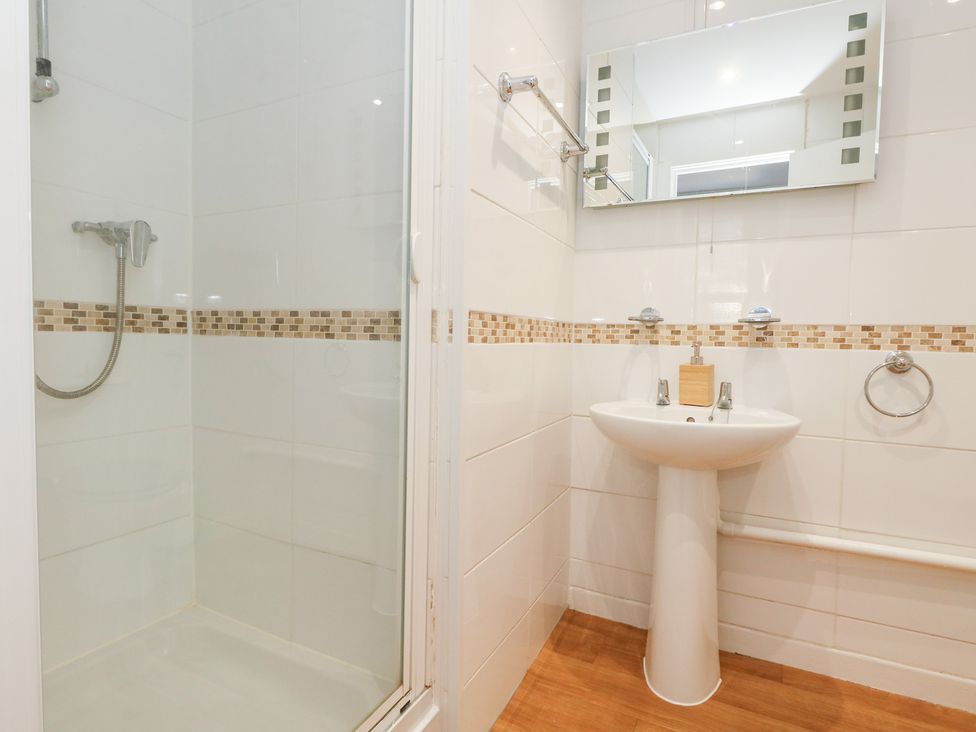 A bathroom with a shower and sink at The Beach Condo in Weymouth