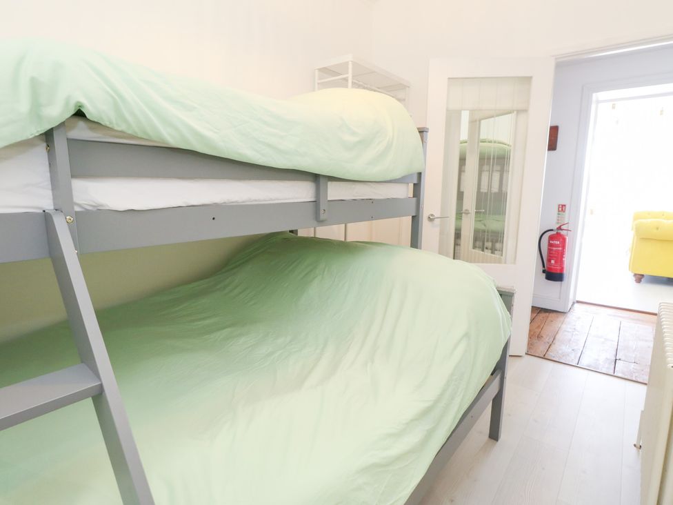 A bedroom with a bunk bed and green bedding at The Beach Condo in Weymouth