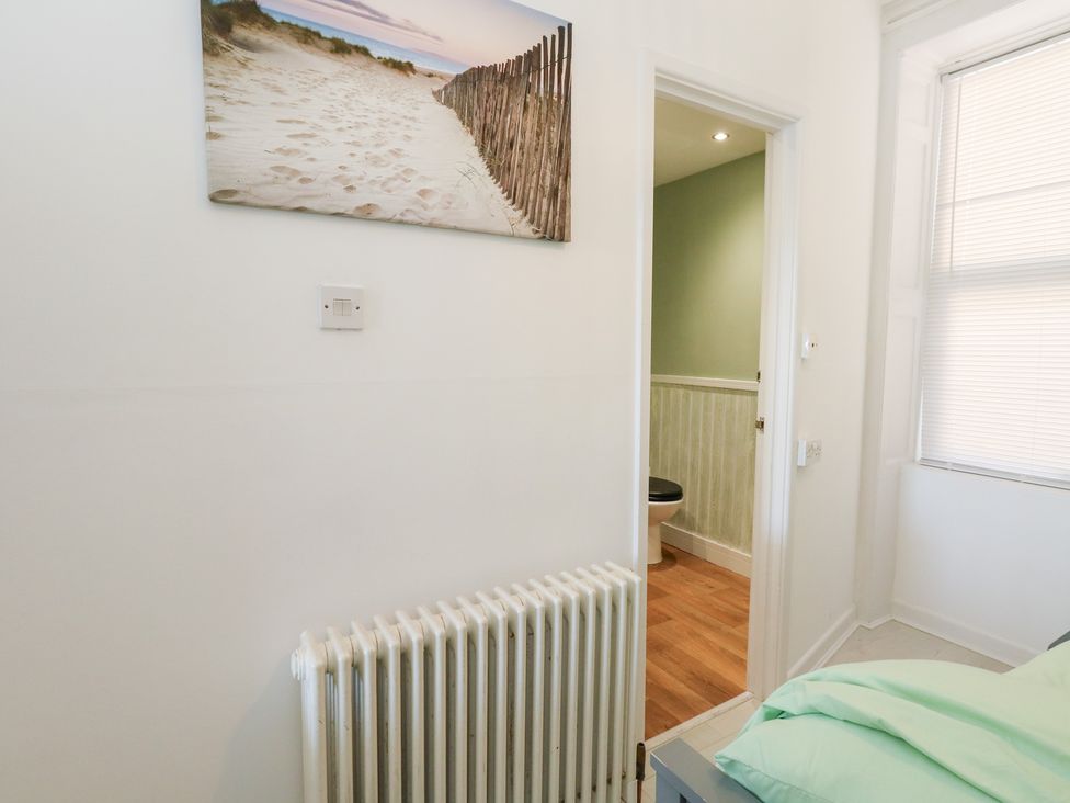 A bedroom with a radiator and a door leading to a toilet at The Beach Condo in Weymouth