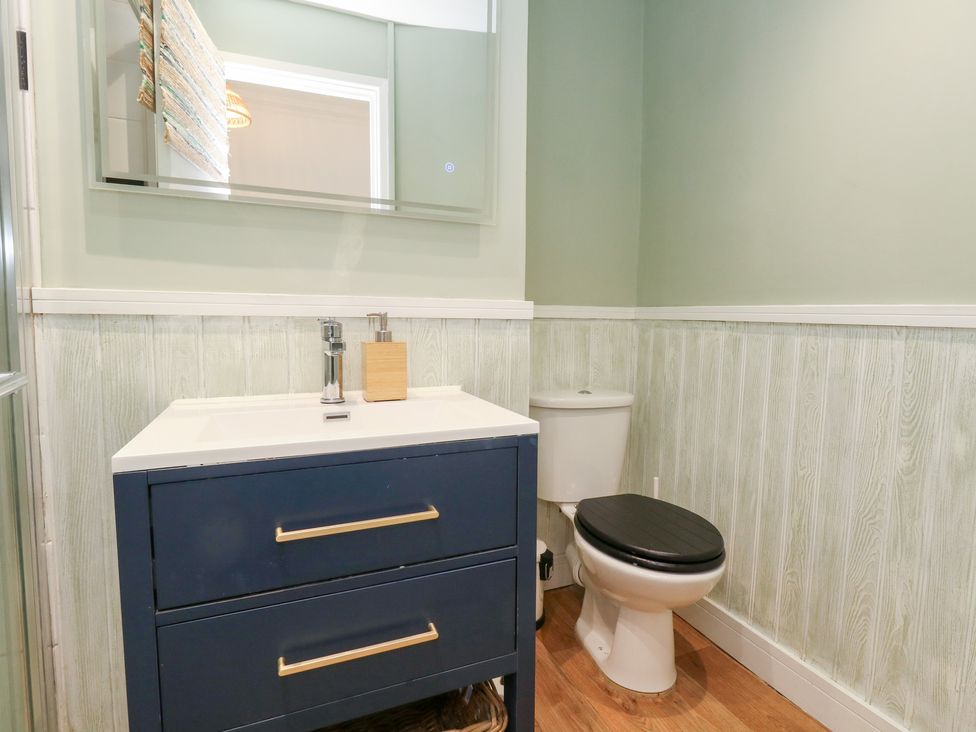 A bathroom with a sink, toilet, and mirror at The Beach Condo in Weymouth