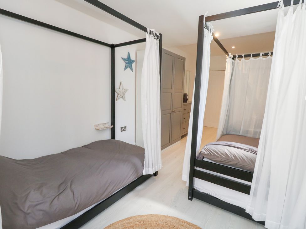 A bedroom with two beds and a wardrobe at The Beach Condo in Weymouth
