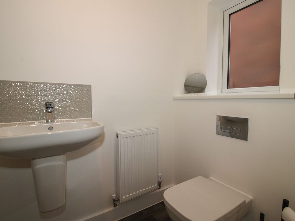 A bathroom featuring a sink, toilet, radiator and window at 10 The Colliery in Telford