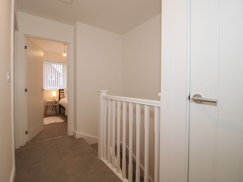 A hallway with a staircase and a door leading to another room at 10 The Colliery Telford