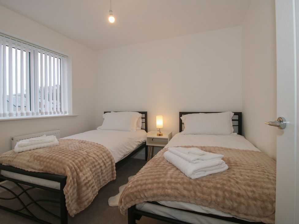 A bedroom with twin beds and a lamp on a side table at 10 The Colliery in Telford